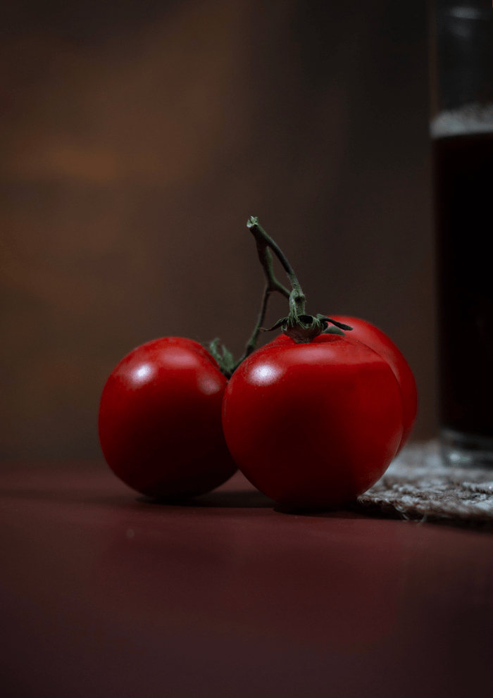 Artistic close-up of fresh red tomatoes on a rustic table with natural lighting, perfect for food and cuisine photography.